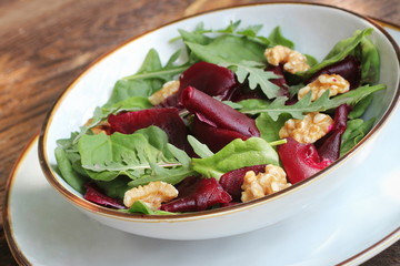 Vegetarian food. Healthy Beet Salad with fresh sweet baby spinach, arugula, nuts