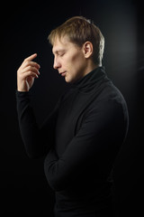 Portrait of determined goodlooking man wearing black shirt, black background.