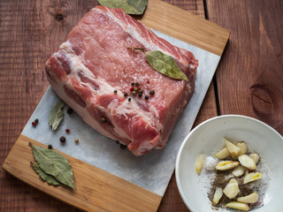 A large piece of pork loin and chopped garlic, bay leaf. Preparation for baking meat