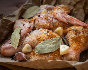 Portioned pieces of chicken meat boned in spices on craft paper lie on a table