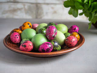 Plate with multi-colored eggs, Kirin and quail on a wooden table for Easter