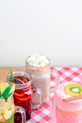 Set of 4 different hot drinks on plaid table. Tea with ginger, lemon, orange, mint, coffee with caramel salted popcorn