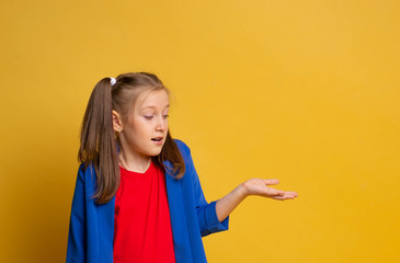 Portrait attractive girl impressed astonished gesture hand wear red t-shirt and blu jacket on yellow background 