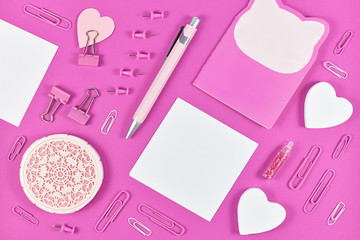 Flat lay with various pink arranged stationery office supplies like pen, note book, blank note paper, pins or retaining clip 