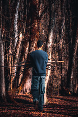 Obraz na płótnie Canvas alone adventurer collecting woods for fire. solo man walking in the forest and collecting woods and enjoying the peace and silence and beauty of nature.