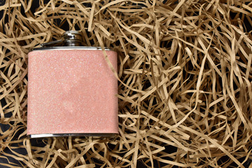 women's pink flask for drinks on a light straw background