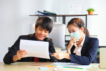 Coworkers are working in business office while wearing medical face mask for protecting and preventing the infection of corona virus or covid-19
