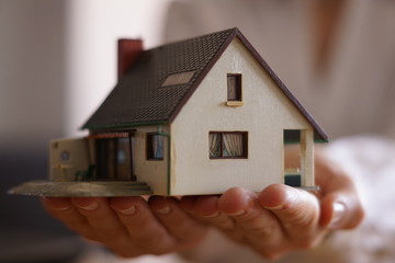 A close up shot of a person holding a miniature house - buying or selling a house concept