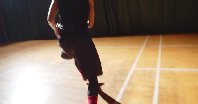 Young curly professional basketball player playing throwing the ball into the basket night darkness silhouette rear view dribbling close-up action