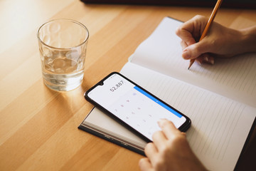 Woman writing on a notebook and using a calculator
