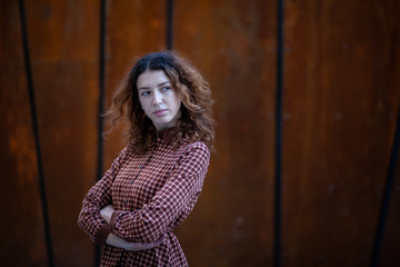 Fototapeta premium Dreaming young woman with spectacular curly red ginger hair looking at camera posing outdoor in downtown street. Female portrait.