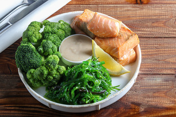 Steamed salmon with broccoli and seaweed salad. Diet healthy eating. On a dark background.