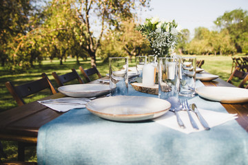 Wooden served table on a background of green nature. Vase with flowers.