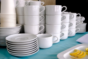 Exposed on stacks of white clean ceramic cups and saucers. The dishes in the restaurant are prepared for tea drinking and coffee drinking.