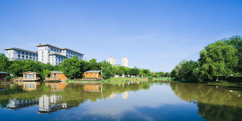 Lake scenery near the city buildings under sunny blue sky