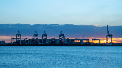 Fototapeta premium Industrial port container crane, seaport at sunset 