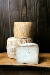Hard cheese kravot or parmesan on a wooden dark board. Cheese knife next to the cheese heads