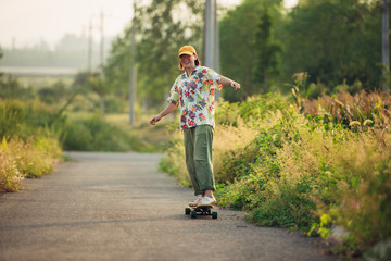 Fototapeta premium A young Asian girl skateboards at sunset
