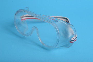 transparent plastic laboratory glasses on blue background.