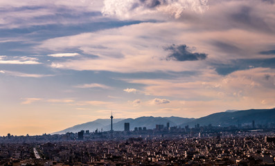 Fototapeta premium Tehran skyline in a beautiful cloudy day with golden hour light Tehran-Iran cityscape with Milad tower in photo and white clouds and lovely blue sky