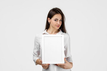 Beautiful smiling woman holding blank board for text on gray background. girl with empty frame for...