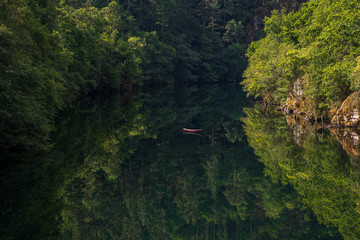 Panoramic view of a tranquil lake with a boat in the middle. There is an impressive reflection that looks like a mirror
