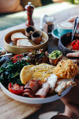 Morning breakfast on a table, waffles with cream, berries, coffee, cappuccino, bowl, omlet with vegetables, bread with butter, avocado cream, vegan food, healthy food, meal.