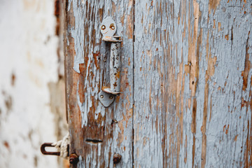 Old wooden door with remnants of old paint. A handle is bolted to the door.