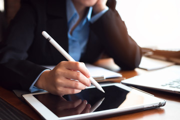 Close up business woman using a digital pen writing on tablet in office.