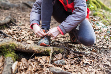 Portrait of girl on hiking forest trip tying shoe laces.