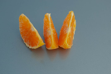 Three slices of mandarin on a blue background