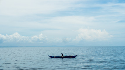 Clear blue seascape with white cloudy background. Blue canoe in the middle