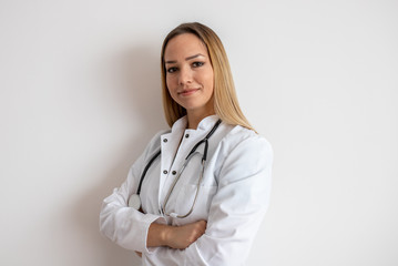 Confident doctor standing arms crossed. Confident young woman doctor. Intern Doctor Young pretty woman in white clothes with a stethoscope posing and smiling.