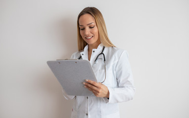 Confident doctor standing with document. Confident young woman doctor. Intern Doctor Young pretty woman in white clothes with a stethoscope posing and smiling