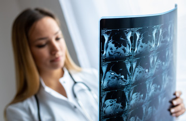 Young female doctor looking at the x-ray picture in her office