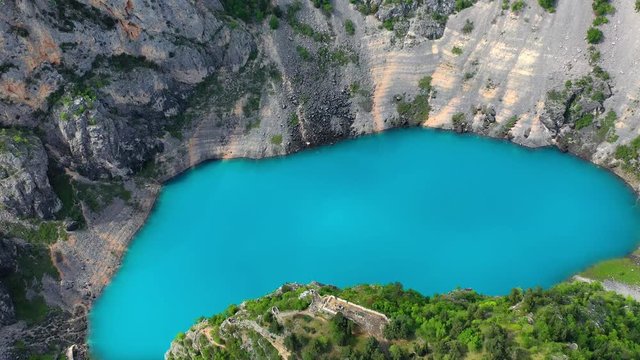 Aerial view beautiful cyan colored lake. Slowly flying away and panning up. Beautiful nature. Blue Lake Imotski, Croatia