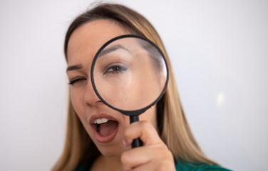 Young attractive woman looking through magnifying glass