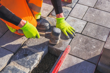 Beton Pflaster Verlegung von einem Arbeiter mit Hammer