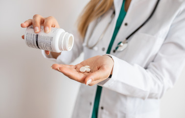Fototapeta premium Female doctor holding pills. Doctor giving medicine