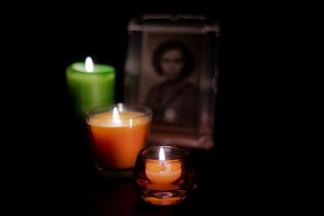 Obraz na płótnie Canvas Three burning candles in front of an woman frame for a portrait. Mourning.