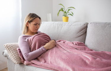 Woman having stomach issues / problems while lying on the couch