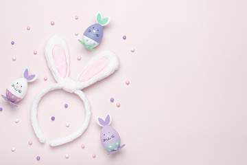 Funny kawaii cute bunny eggs and bunny rabbit ears for kids in pastel colors on pink table top, Easter holiday concept. Easter decoration for kids still life, copy space