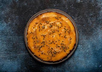 Homemade mango upside down cake with and passion fruit on a dark rustic background. Delicious vegetarian sweet food concept. Horizontal view from above. Copy space.