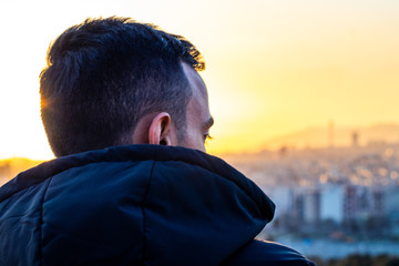 an alone man looking though a city skyline at a beautiful sunset and thinking.