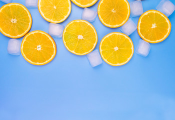 Orange slices and ice cubes on a blue background. Copy space.