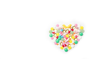 Heart made of multi-colored pills on a white background. Health and medicine concept