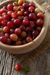 Red gooseberry in a bowl on wooden surface