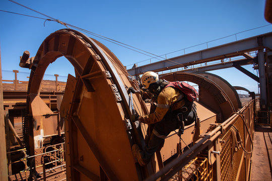 Industrial rope access abseiler inspector wearing full body safety harness CS5 handglove protection using tension line an anchor point abseiling inspecting fastening nuts bolts with torque wrench tool