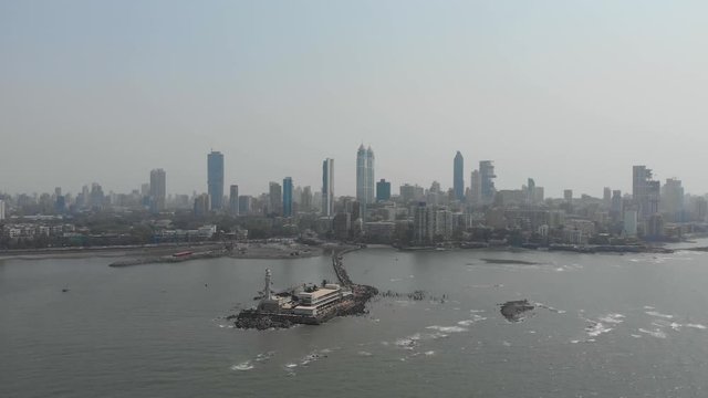 Dolly drone shot of Haji Ali dargah sea mosque with Mumbai skyscrapers in the background