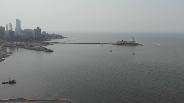 Falling shot of Haji Ali dargah mosque with Western freeway costal highway construction project in the foreground